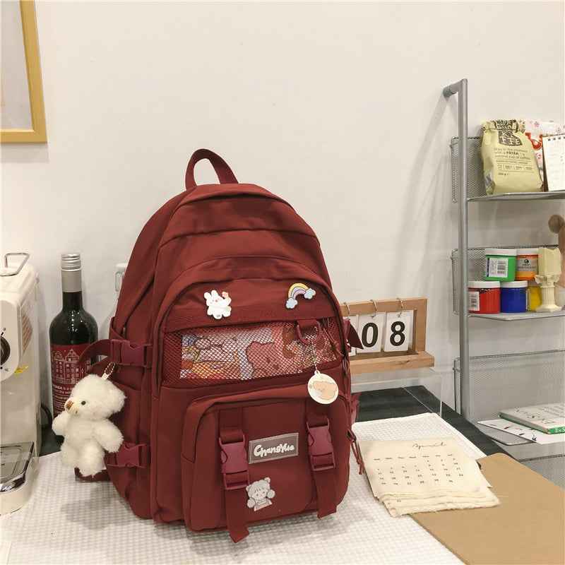 Burgundy canvas backpack with mesh front panel and small bear applique
