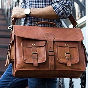 Leather briefcase held by a man with shoulder strap and flap front buckle pockets