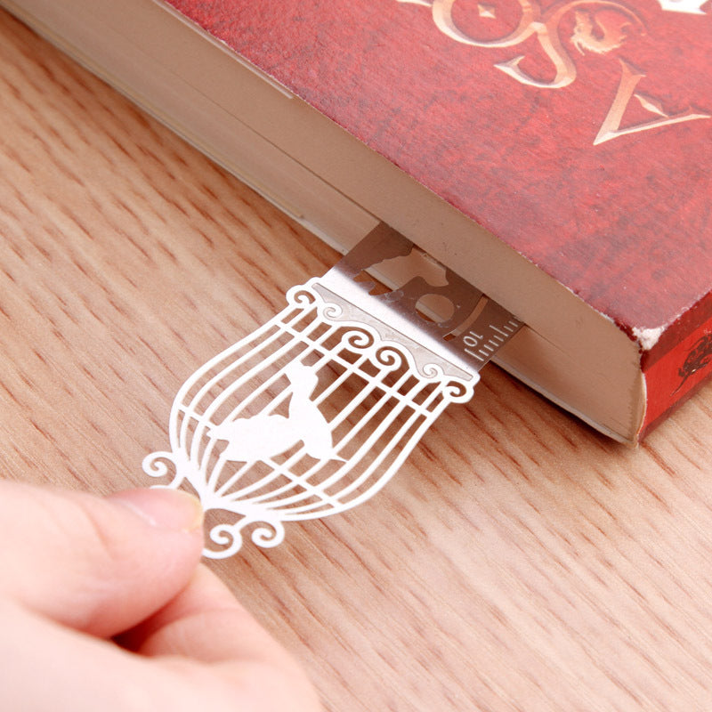 White hollow metal birdcage bookmark with black cord, close-up on charm detail.