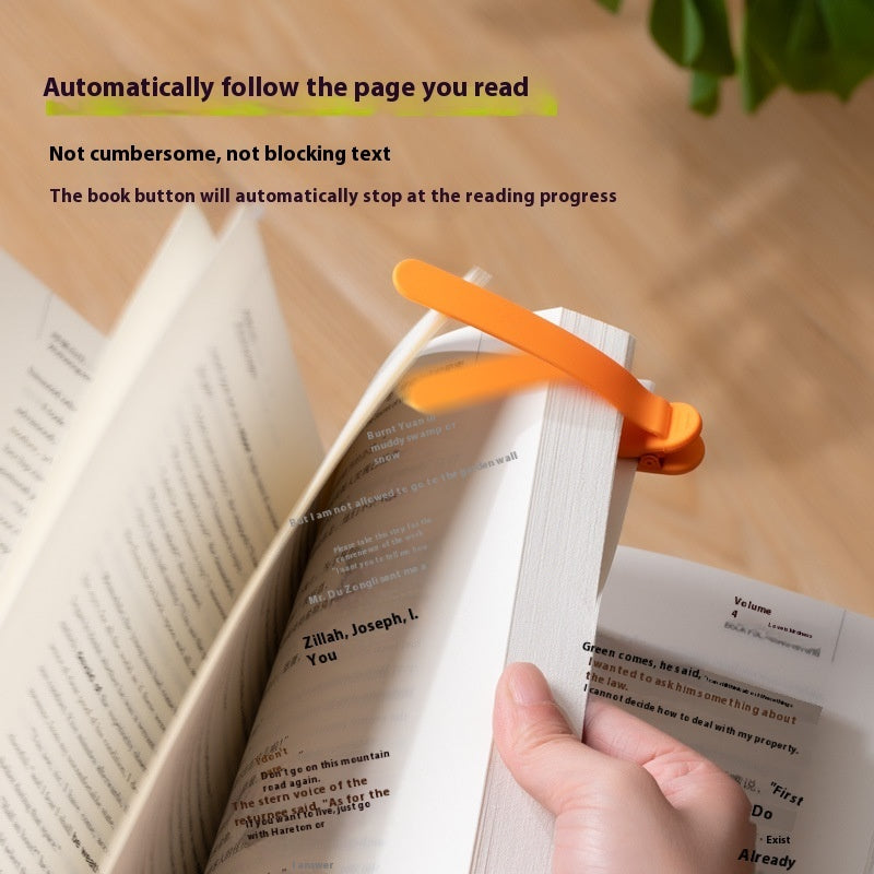 Silicone reading bookmark clip, orange, clipped to an open book with a hand holding it