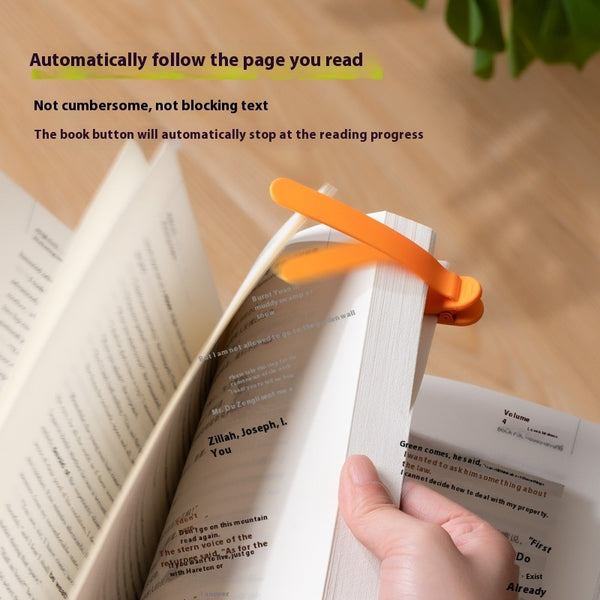 Silicone reading bookmark clip, orange, clipped to an open book with a hand holding it
