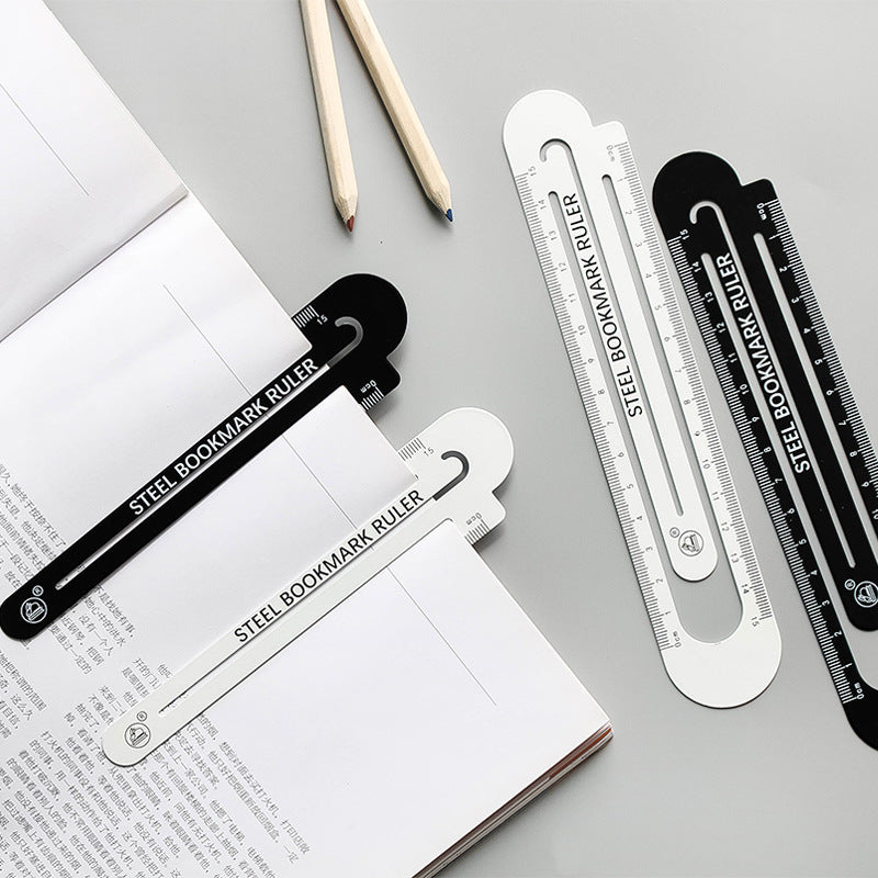 Steel bookmark ruler pack in black and white hollow 12 cm, with pencils on paper.