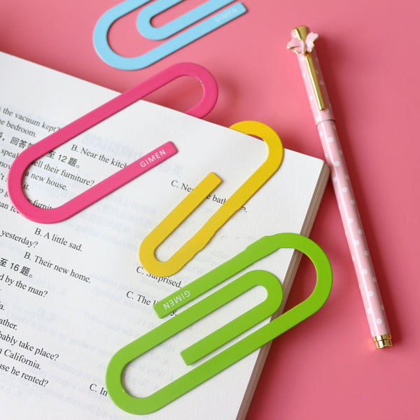 Colored paper clip bookmarks in pink, blue, yellow, and green holding a book page corner