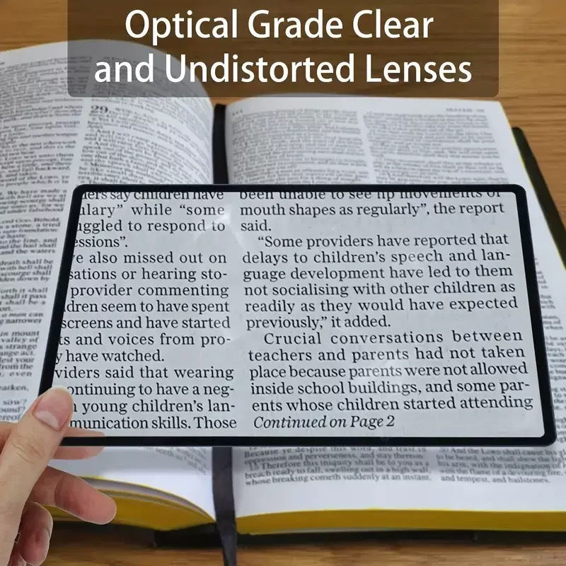 Hand holds magnifying glass bookmark lens over book text with black frame
