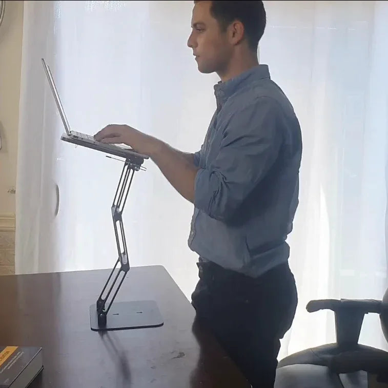Standing desk setup using an adjustable laptop riser to elevate screen height for improved posture and active work positioning
